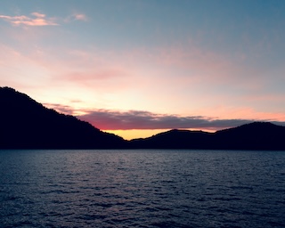 Photography by Keagen Thomson of Crescent Lake Washington, a mountainous blue lake at sunset