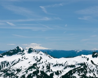 Photography by Keagen Thomson of Mount Rainier Washington, Snowy peak against the horizon with Mt. Hood in the distance